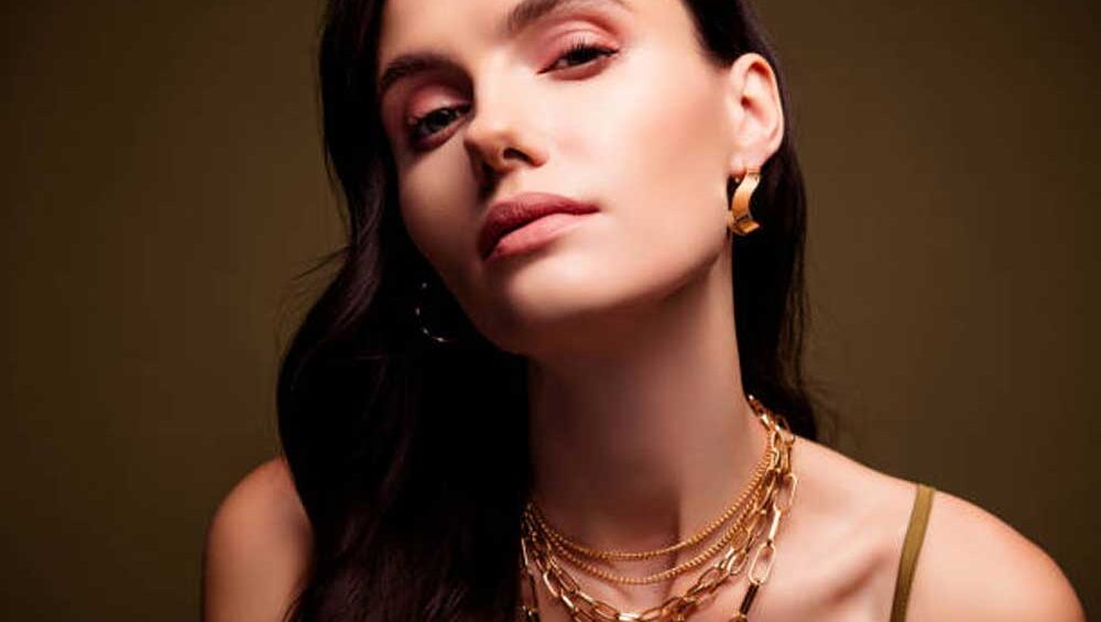 Model showcasing a chic look with layered gold necklaces and bold gold hoop earrings, exuding modern elegance and confidence.