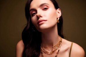 Model showcasing a chic look with layered gold necklaces and bold gold hoop earrings, exuding modern elegance and confidence.