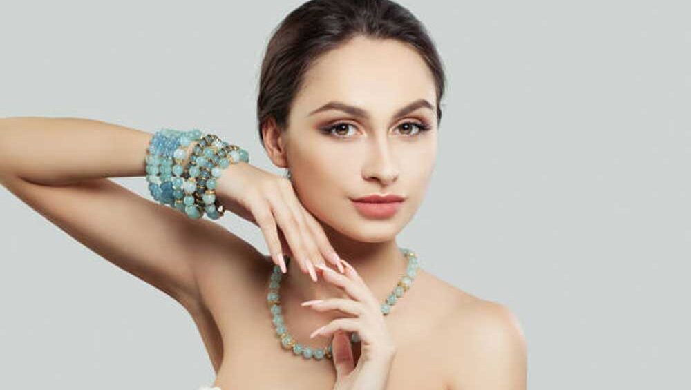 Elegant woman wearing matching blue gemstone necklace and bracelets, showcasing a harmonious jewelry look.