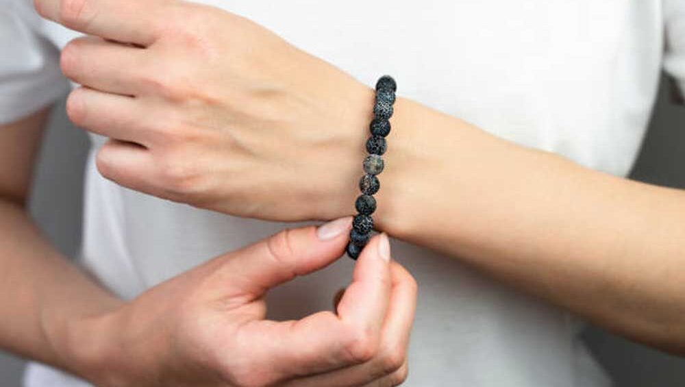 Close-up of a person wearing a bracelet made from black lava stones, showcasing the natural texture and unique appeal of stone jewelry.