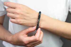 Close-up of a person wearing a bracelet made from black lava stones, showcasing the natural texture and unique appeal of stone jewelry.