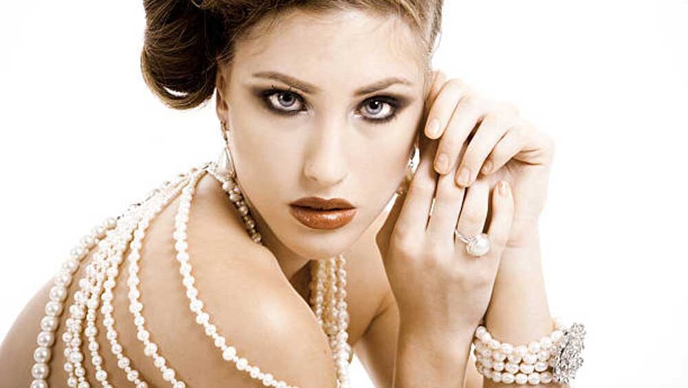 Elegant woman adorned with layered pearl necklaces, a pearl bracelet, and a pearl ring, showcasing a timeless look in jewelry.