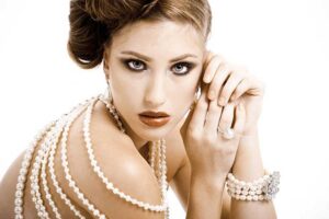 Elegant woman adorned with layered pearl necklaces, a pearl bracelet, and a pearl ring, showcasing a timeless look in jewelry.