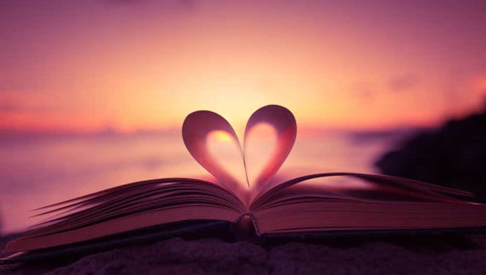 Open book with heart-shaped pages at sunset, symbolizing love and a new beginning.