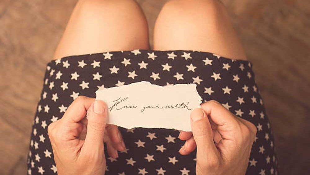 A person holding a torn piece of paper with the handwritten words 'Know your worth,' symbolizing self-respect, empowerment, and love.