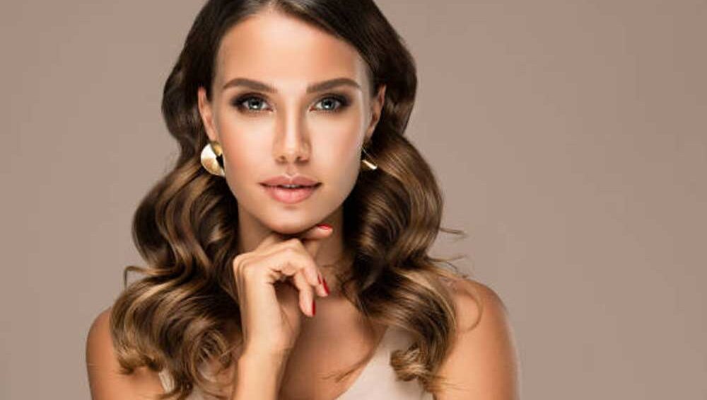Woman with sleek hairstyle wearing minimalist gold earrings, showcasing a sophisticated jewelry look.