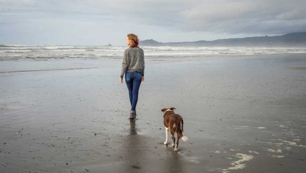 A woman walking along the beach with her dog, symbolizing freedom, healing, and breaking free from toxic relationships.