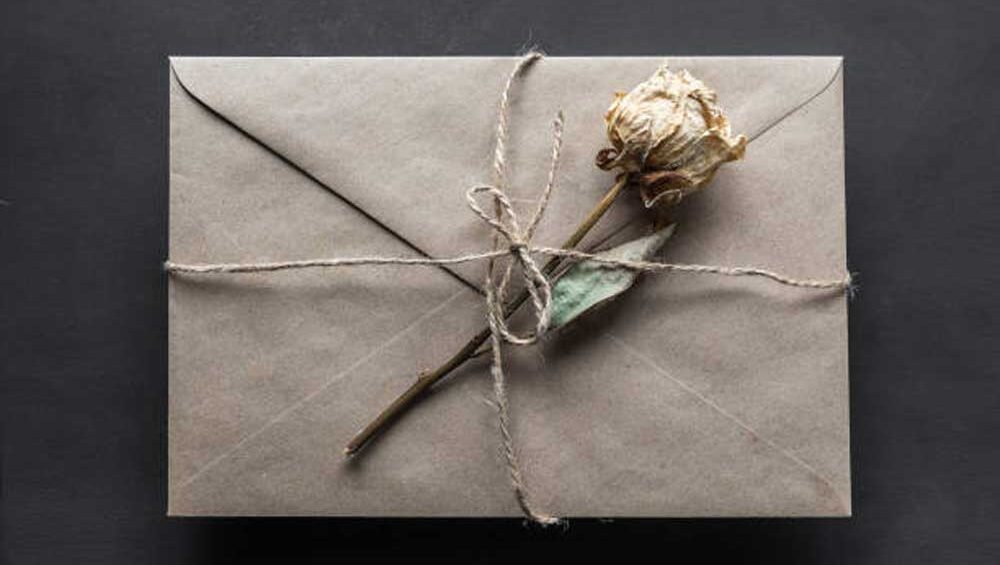 A sealed kraft envelope tied with twine, adorned with a dried rose, symbolizing closure, finality, and letting go of the past.