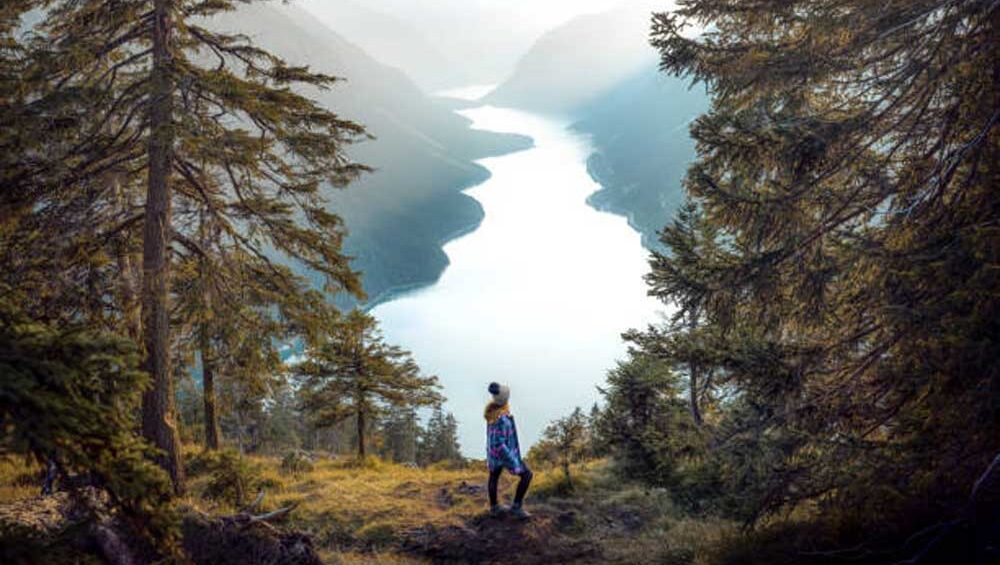 Woman overlooking a mountain lake at sunrise, symbolizing clarity and self-discovery