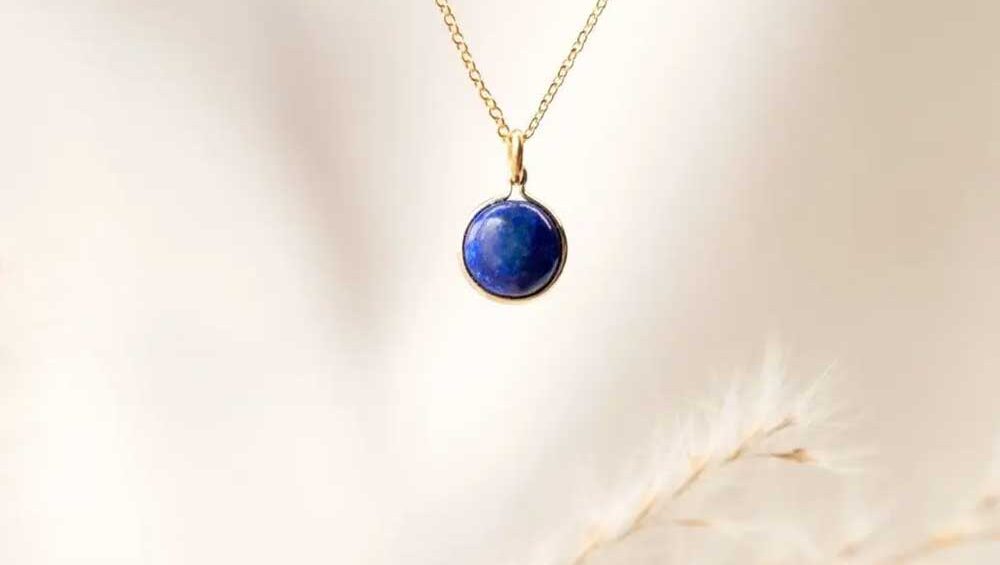 Lapis lazuli birthstone pendant necklace on a delicate gold chain with a soft neutral background