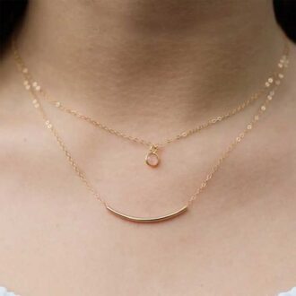 Close-up of a woman wearing a gold-filled curved tube bar necklace layered with a small gold circle pendant on delicate chains.