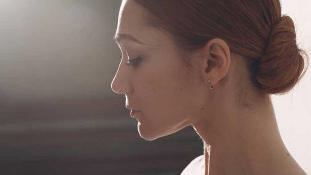 Profile of a calm woman with eyes closed, softly lit, symbolizing peace and emotional integration.