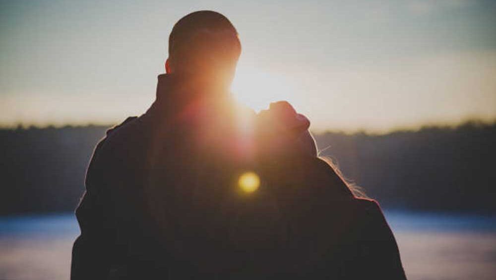 Silhouetted couple leaning into each other at sunrise, symbolizing conscious love and emotional wholeness after healing.