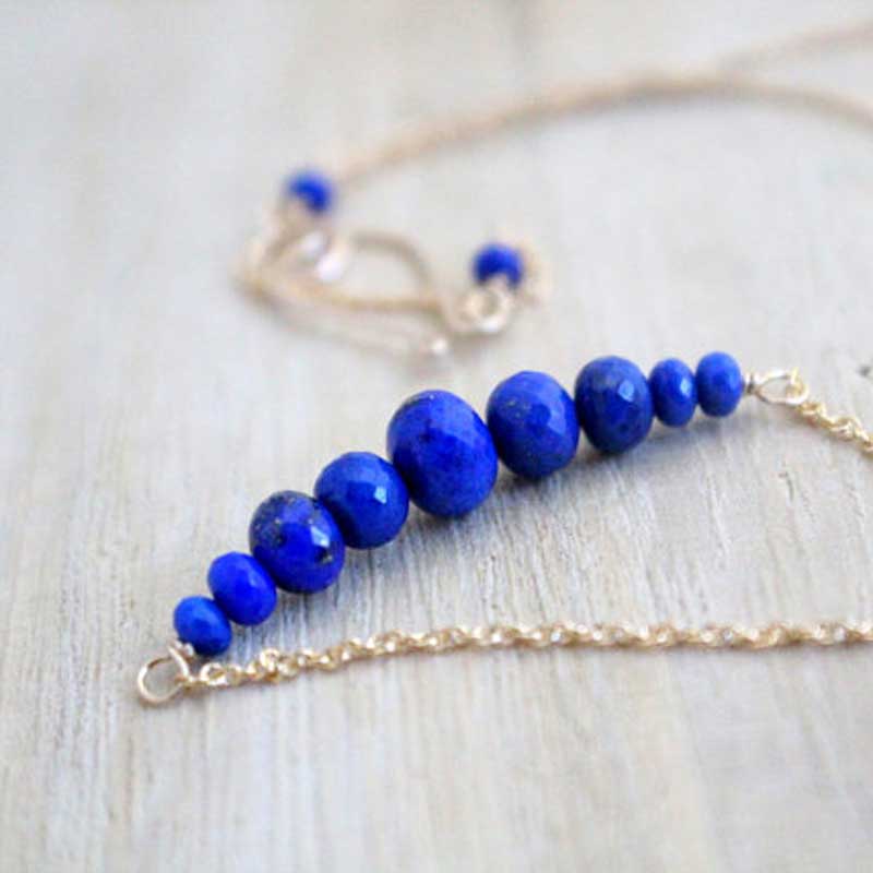 Close-up of the Circlet Lapis Lazuli Bar Necklace by Saressa Designs, showcasing graduated faceted rondelles on a gold filled chain.