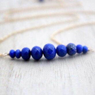 Close-up of a Lapis Lazuli bar necklace featuring faceted rondelle gemstones arranged in a gradient on a gold filled chain by Saressa Designs.
