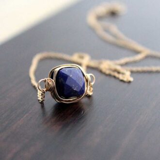 Close-up of Saressa Designs Lapis Lazuli Bezel Wrapped Necklace showing faceted gemstone wrapped in wire on a gold-filled chain.