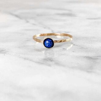 Dainty lapis lazuli gemstone ring with a hammered 14k gold-filled band, displayed on marble.