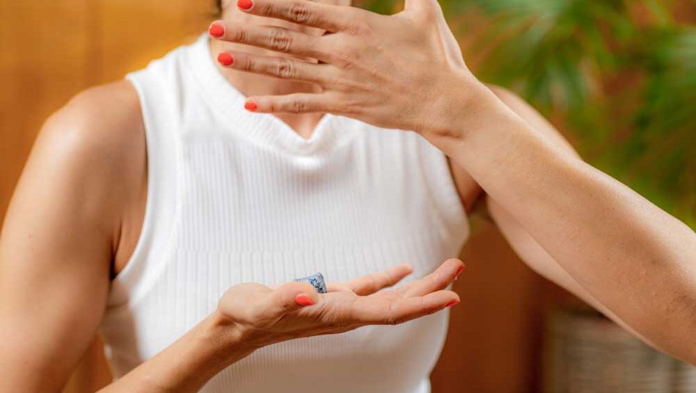 Woman practicing throat chakra healing with a lapis lazuli crystal in hand, promoting communication and inner truth.
