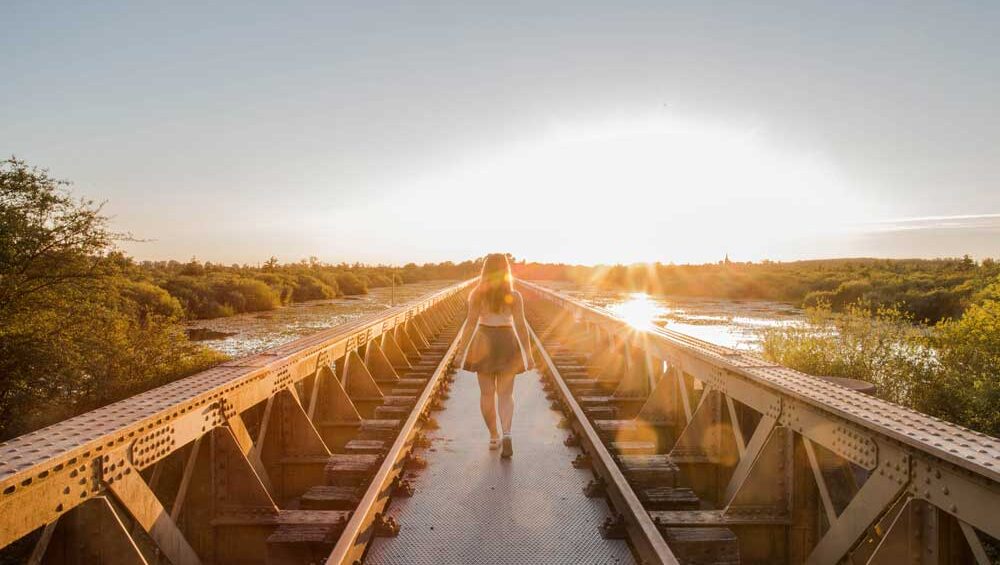 Woman walking alone across a sunlit bridge, symbolizing emotional journey and healing from avoidant attachment.