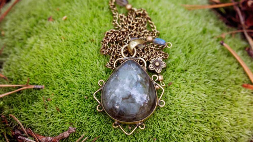 Handcrafted labradorite pendant with brass chain resting on moss, inspired by Scandinavian jewelry