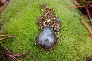 Handcrafted labradorite pendant with brass chain resting on moss, inspired by Scandinavian jewelry