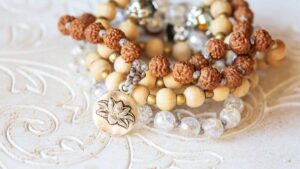 Wooden and gemstone beaded bracelets with a lotus charm symbolizing mindfulness, calm, and balance on a decorative background.