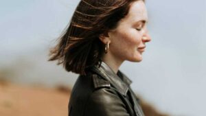 Woman in peaceful reflection wearing gold hoop earrings, symbolizing how jewelry helps us reconnect with ourselves.