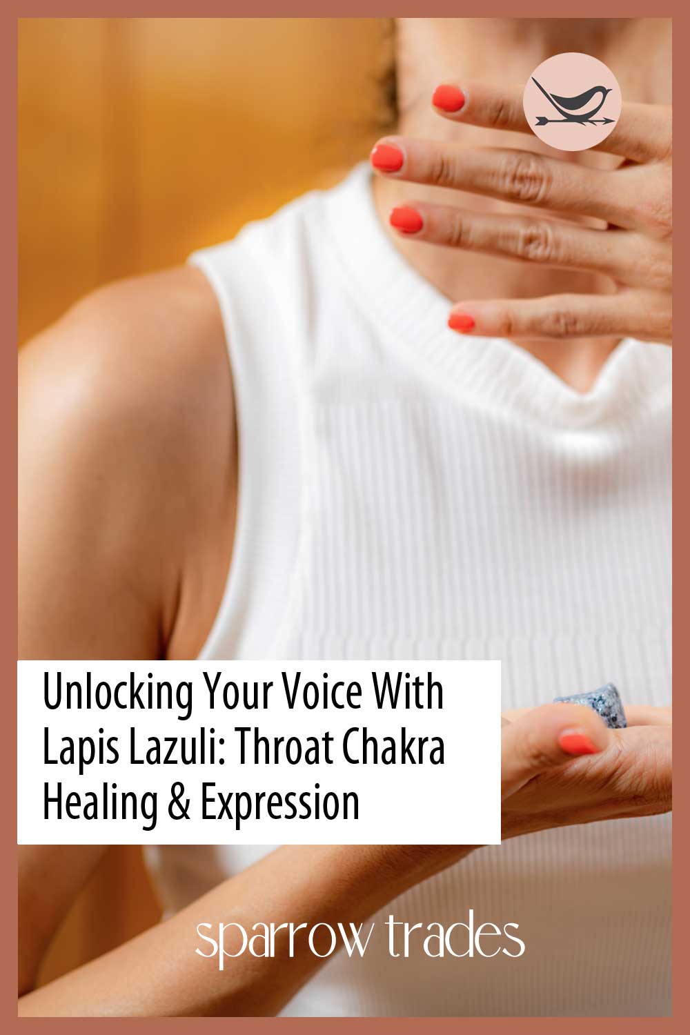 Woman gently touching her throat while holding a piece of lapis lazuli, symbolizing throat chakra healing and self-expression.