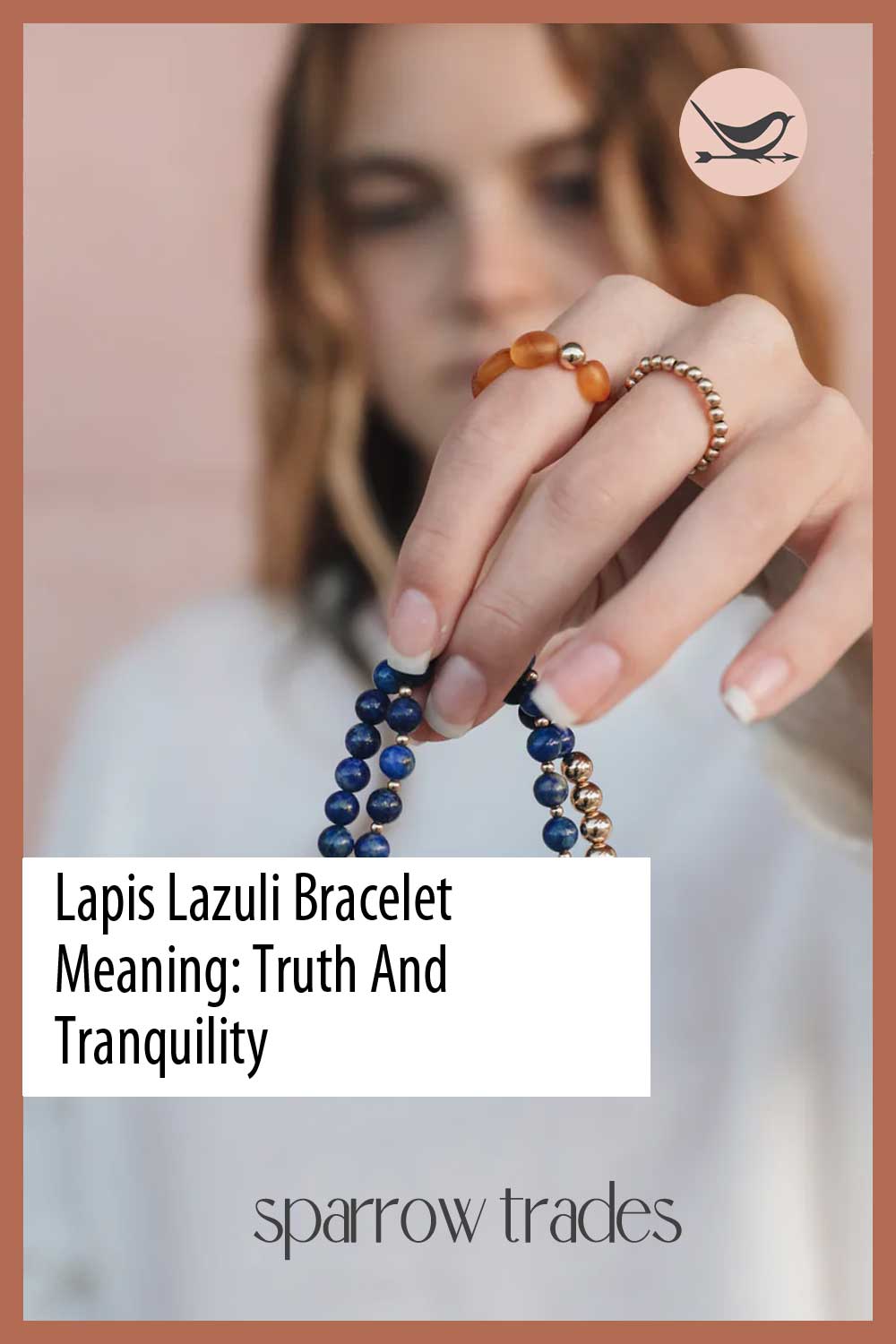 Woman holding a lapis lazuli beaded bracelet with gold accent beads, blurred background, text overlay reads “Lapis Lazuli Bracelet Meaning: Truth And Tranquility” with Sparrow Trades logo.