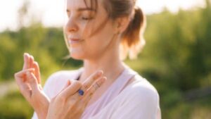Woman meditating outdoors wearing a lapis lazuli ring, symbolizing third eye chakra activation and inner clarity.