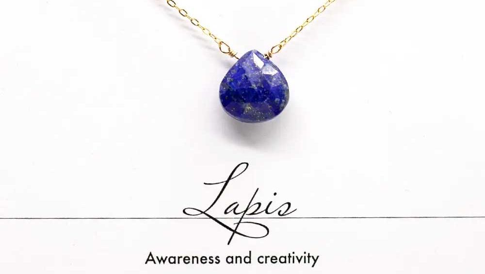 Faceted lapis lazuli teardrop pendant on a gold chain, symbolizing awareness and creativity.