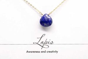 Faceted lapis lazuli teardrop pendant on a gold chain, symbolizing awareness and creativity.