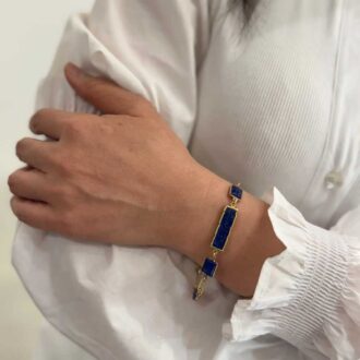 Woman wearing the Lapis Slice Toggle Bracelet with natural lapis lazuli stones on gold-plated silver chain