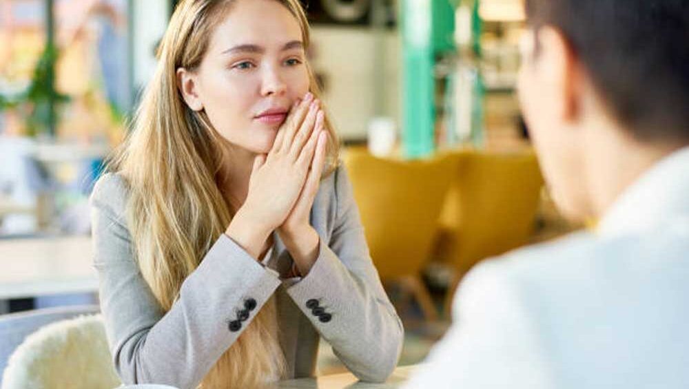 A woman in a café listening attentively to someone across the table, showing engagement and understanding.