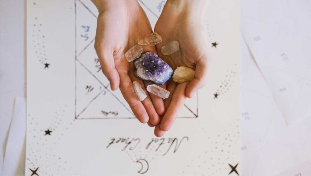 Hands holding amethyst and rose quartz healing crystals