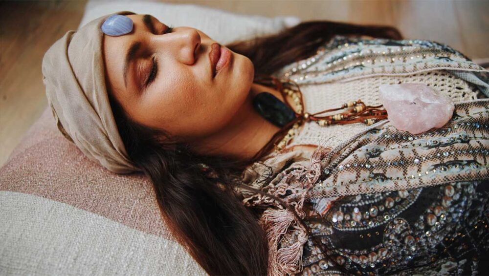 Woman in meditation with healing crystals placed on forehead and chest for chakra crystal healing