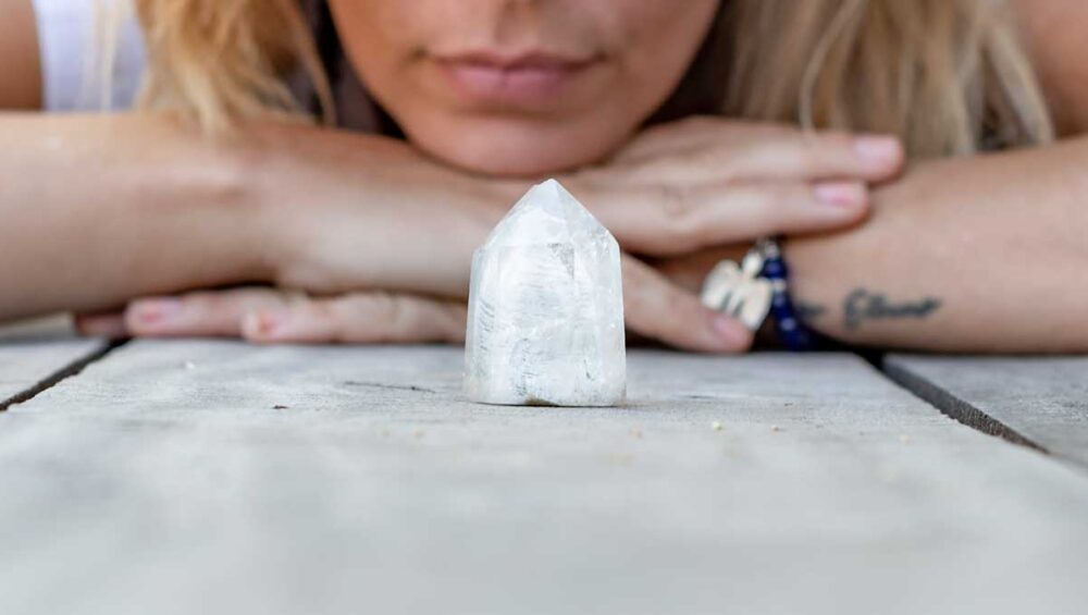 Woman reflecting with a clear quartz crystal for healing and wellness
