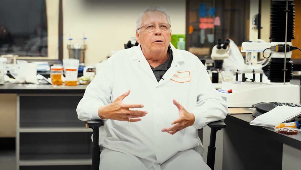 My dad wearing a lab coat, seated in a laboratory, sharing his knowledge and experience surrounded by scientific equipment.