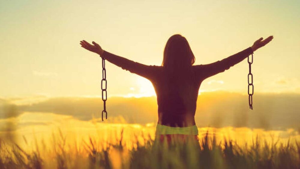 Woman breaking free from chains at sunrise, symbolizing healing from narcissistic family dynamics