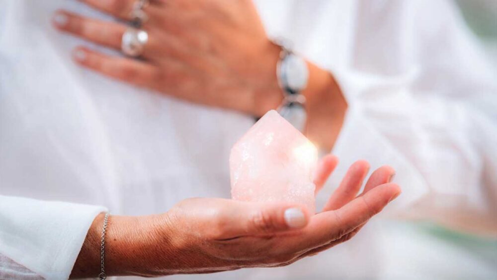 Woman holding rose quartz crystal over heart for self-love affirmations