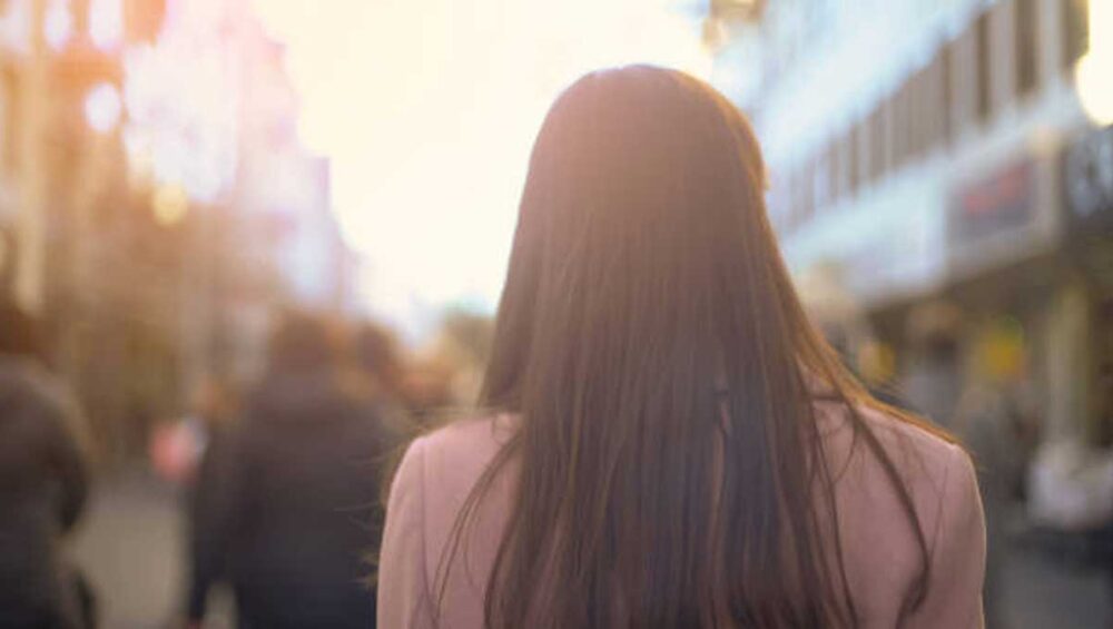 Woman walking toward sunlight in a crowd, symbolizing breaking free from toxic family dynamics.