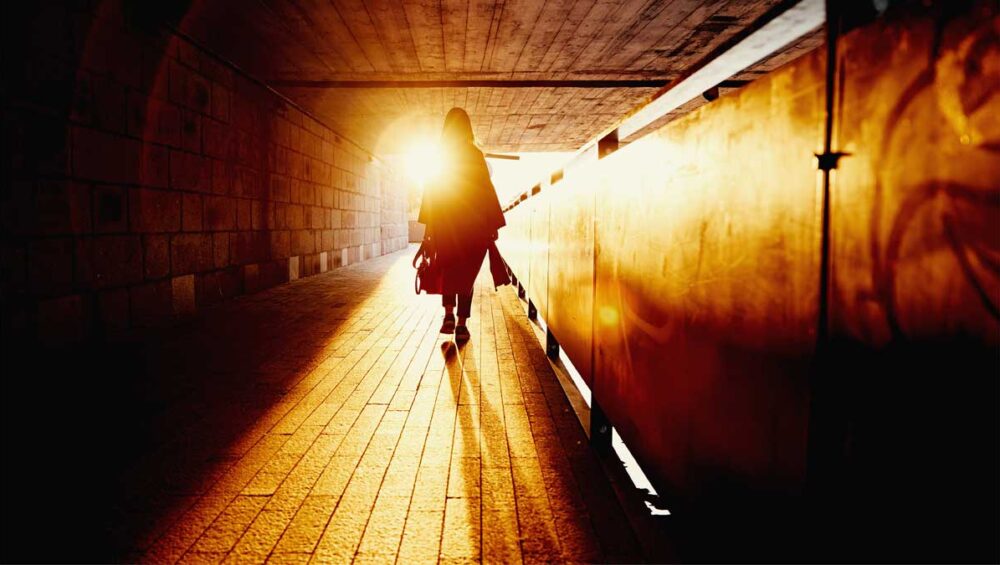 Woman walking through a tunnel into bright sunlight, symbolizing healing from emotional invalidation and the journey toward emotional awareness.