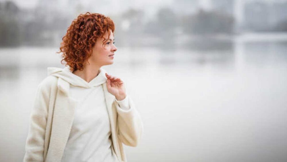 Woman in soft light reflecting near a calm lake, symbolizing healing from emotional numbness