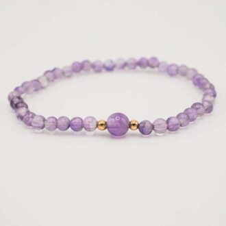 Amethyst beaded stretch bracelet with a larger 6mm center bead and two small gold-filled accents