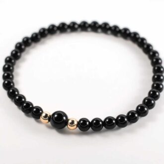 Black Onyx beaded bracelet with a central larger onyx bead and two gold-filled accent beads.