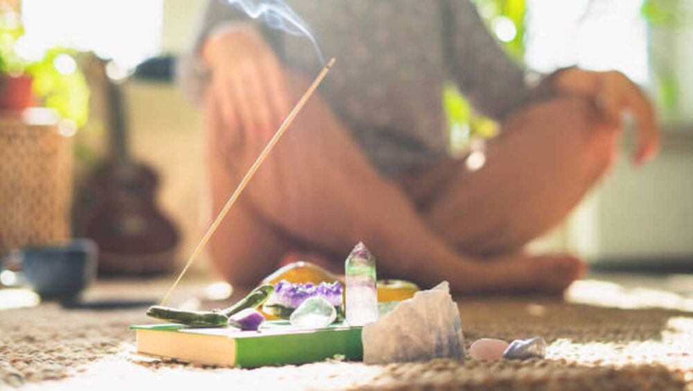 Person meditating with crystals and incense for inner peace