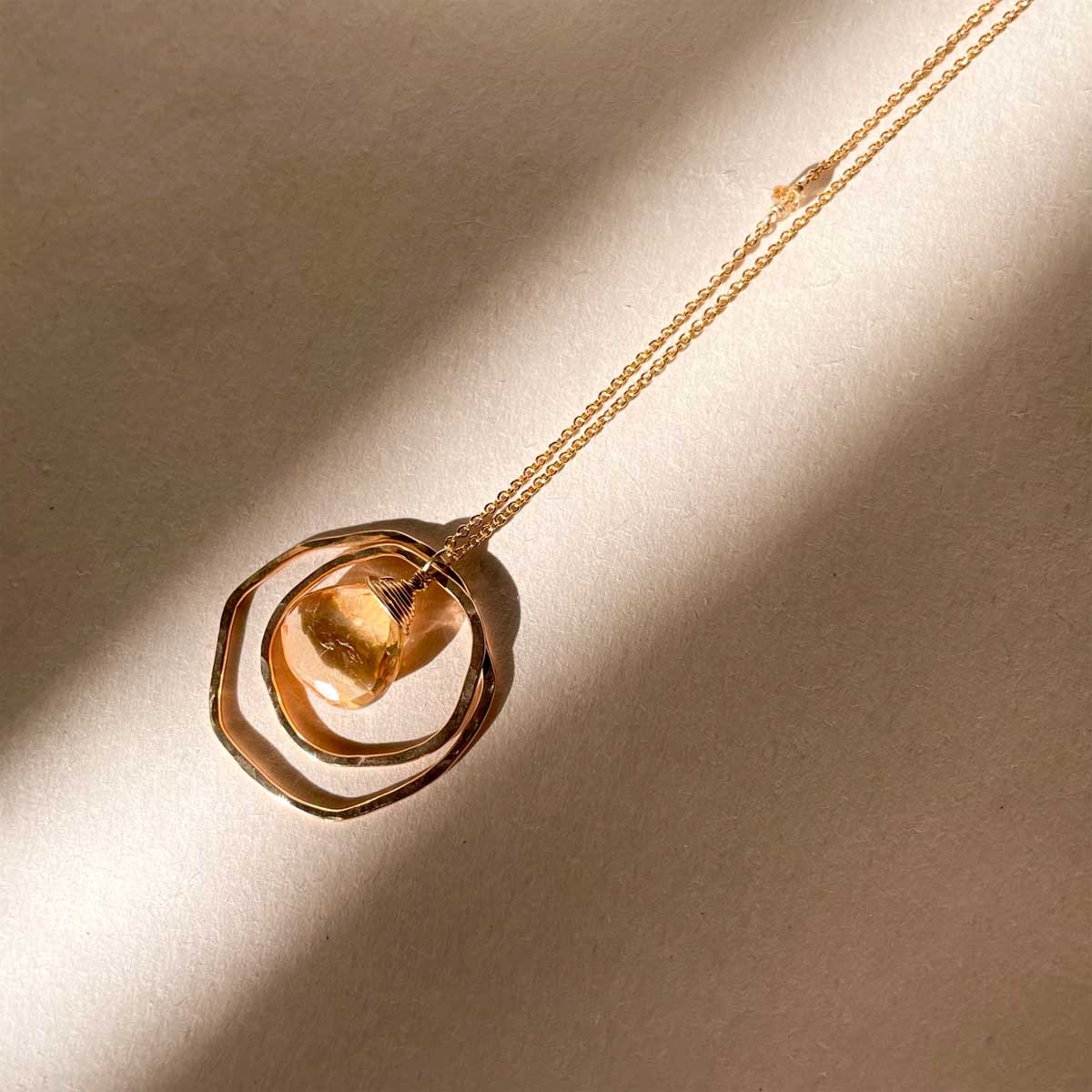 Gold chain necklace with two hammered circles framing a wire-wrapped citrine stone