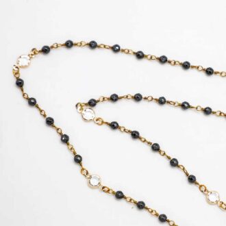 Hematite bead chain necklace with gold links and beveled glass accents on a long strand design.