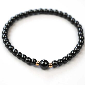 Hematite horizon bracelet with polished beads featuring one larger hematite stone accented by two 14K gold-filled beads.