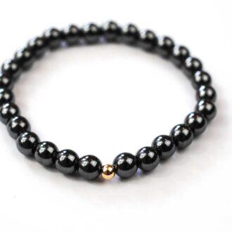 Hematite solo core bracelet with polished beads and a single 14K gold-filled accent bead on elastic cord.